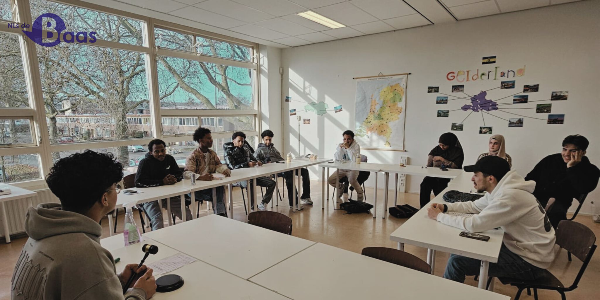 Een groep jonge cursisten volgt samen een Nederlandse les in een licht klaslokaal in Arnhem